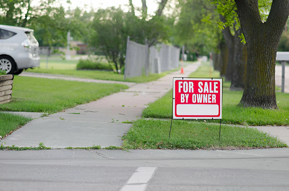 For sale by owner sign on green lawn near sidewalk